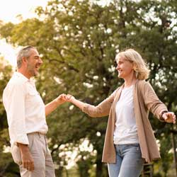 Older couple dancing looking at each other in the park.